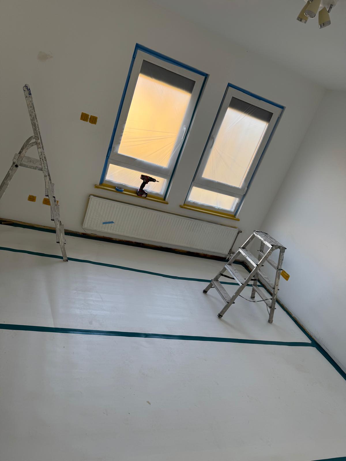 Zimmer mit abgeklebten Fenstern und Abdeckvlies vor dem Streichen